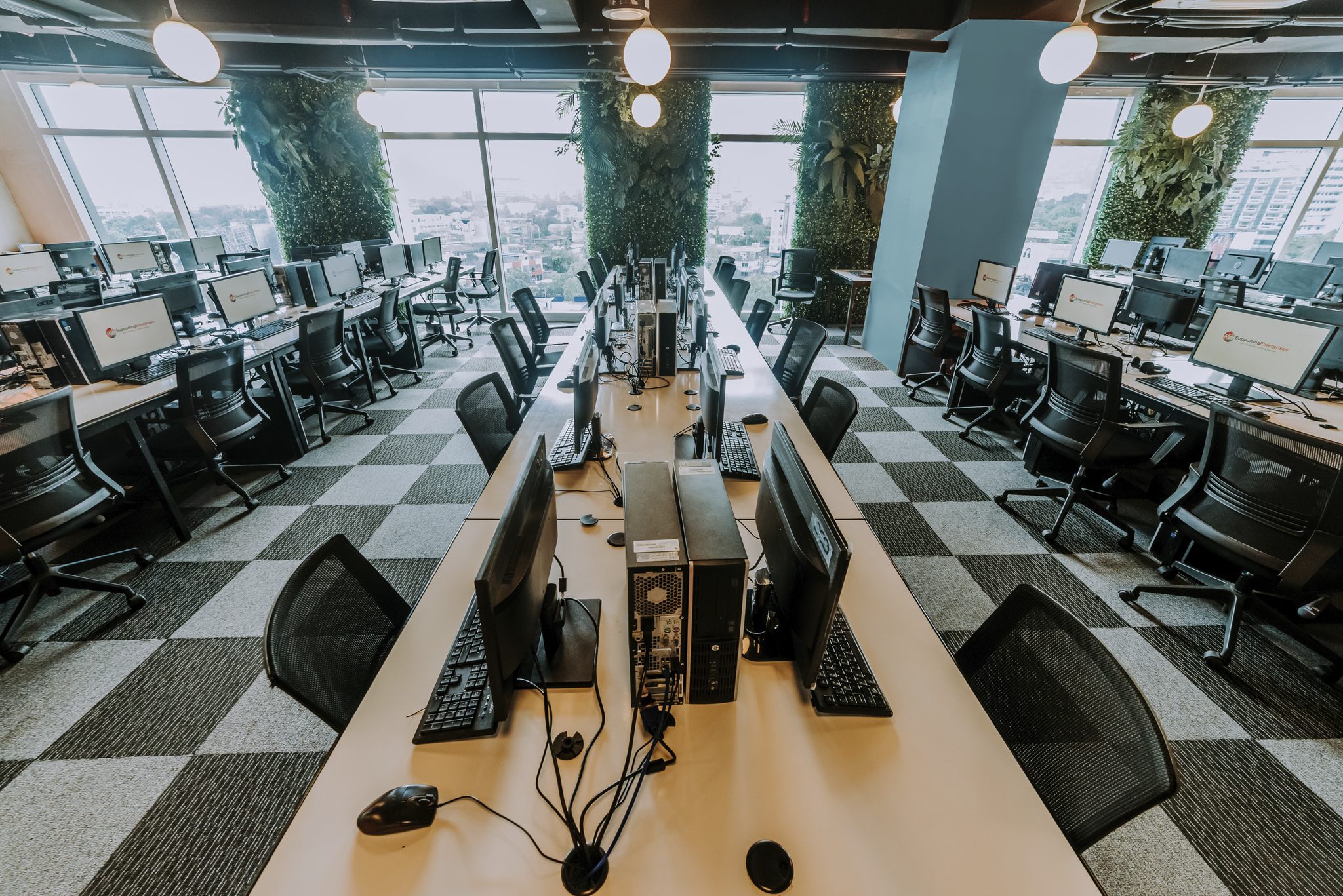 Call center chairs lined up in a checkered floor and wooden tables