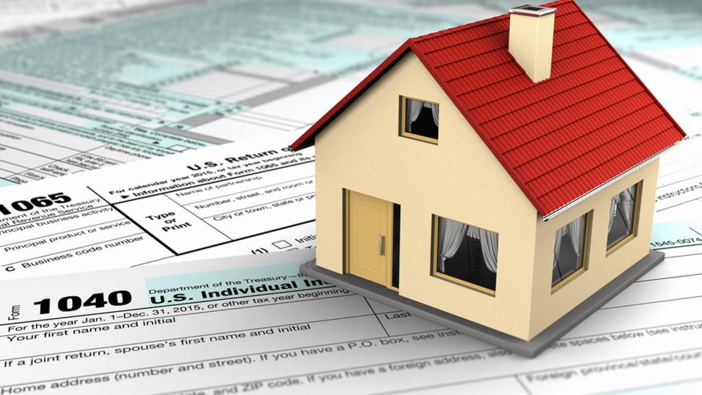 Real Estate documents below a miniature home paper weight