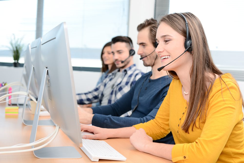 A woman and her call center colleagues enthusiastically taking calls 