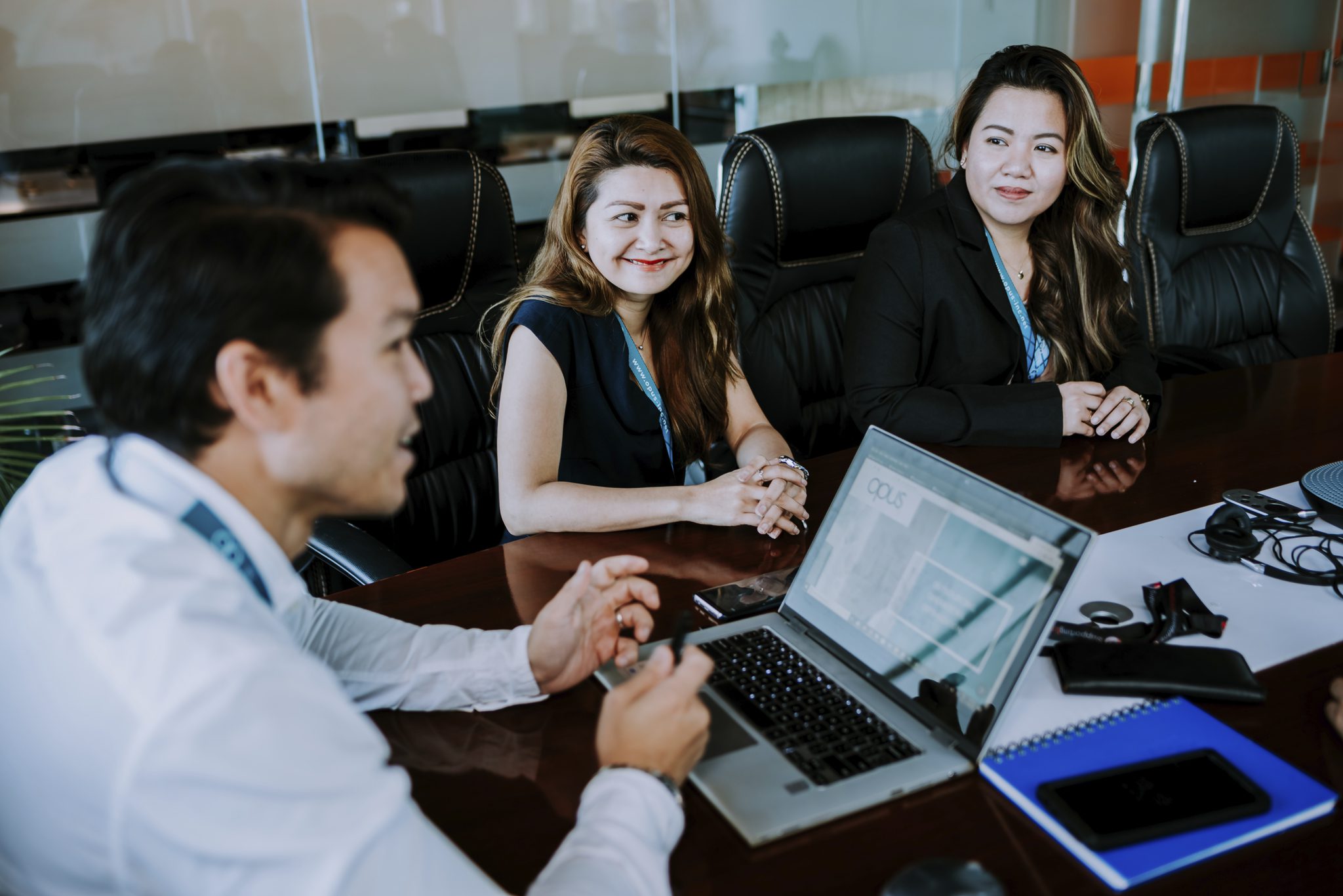 An Outsourcing Executive in white and 2 Female Remote EStaff dressed in black conversing in a table