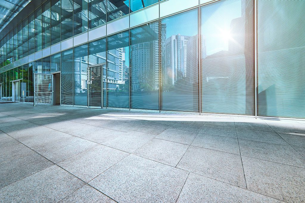 A logistics office with reflective glass windows and pavement on foreground